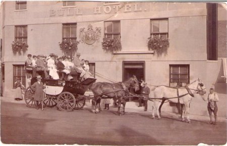 Horse drawn coach full of people in front of Bull Hotel