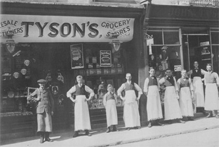 Men in white aprons lined up in front of shop