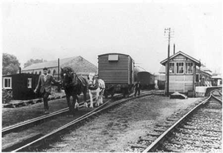 Horses pulling wagon on rail tracks.